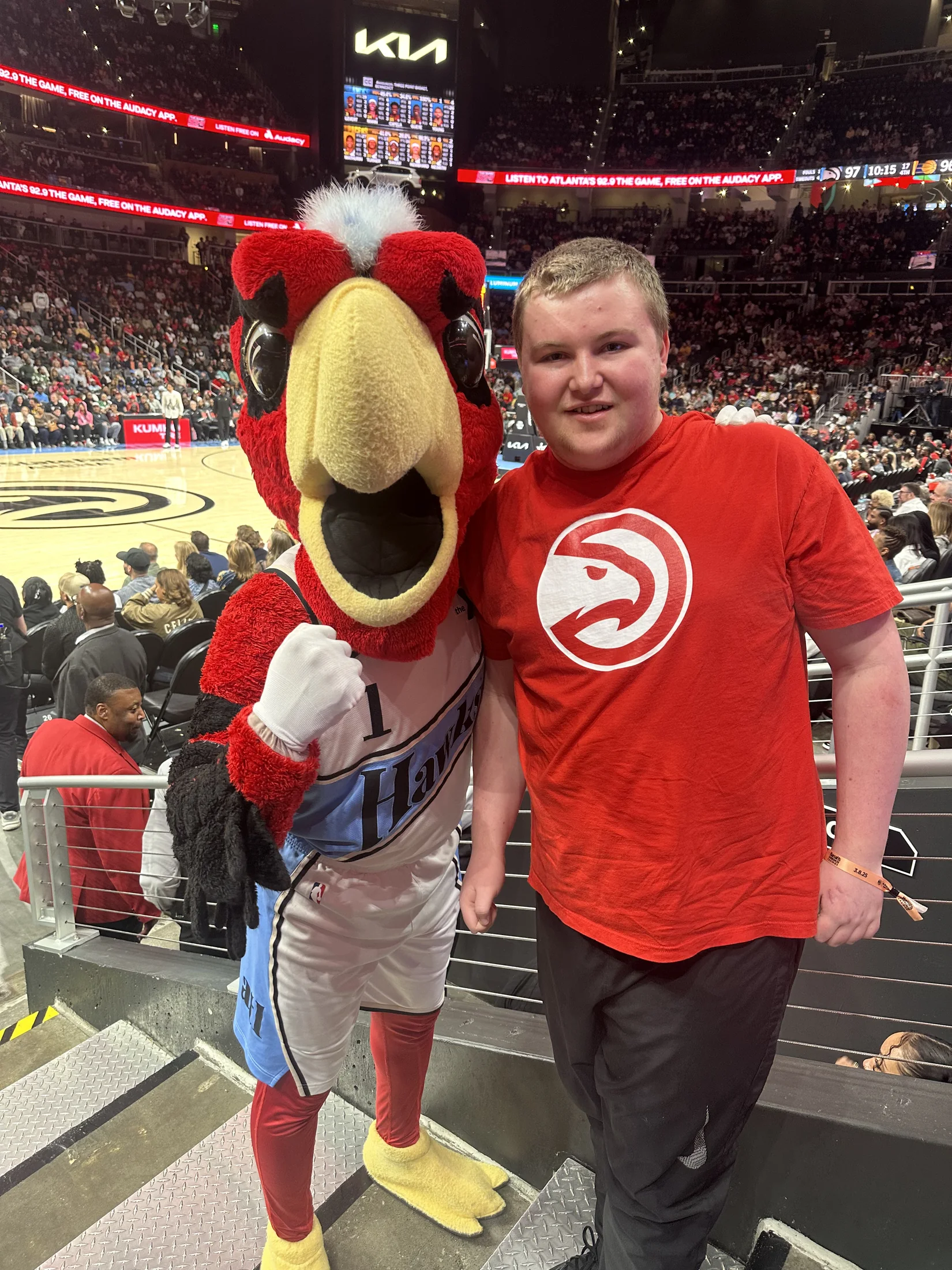Tommy smiling with Harry the Hawk at State Farm Arena