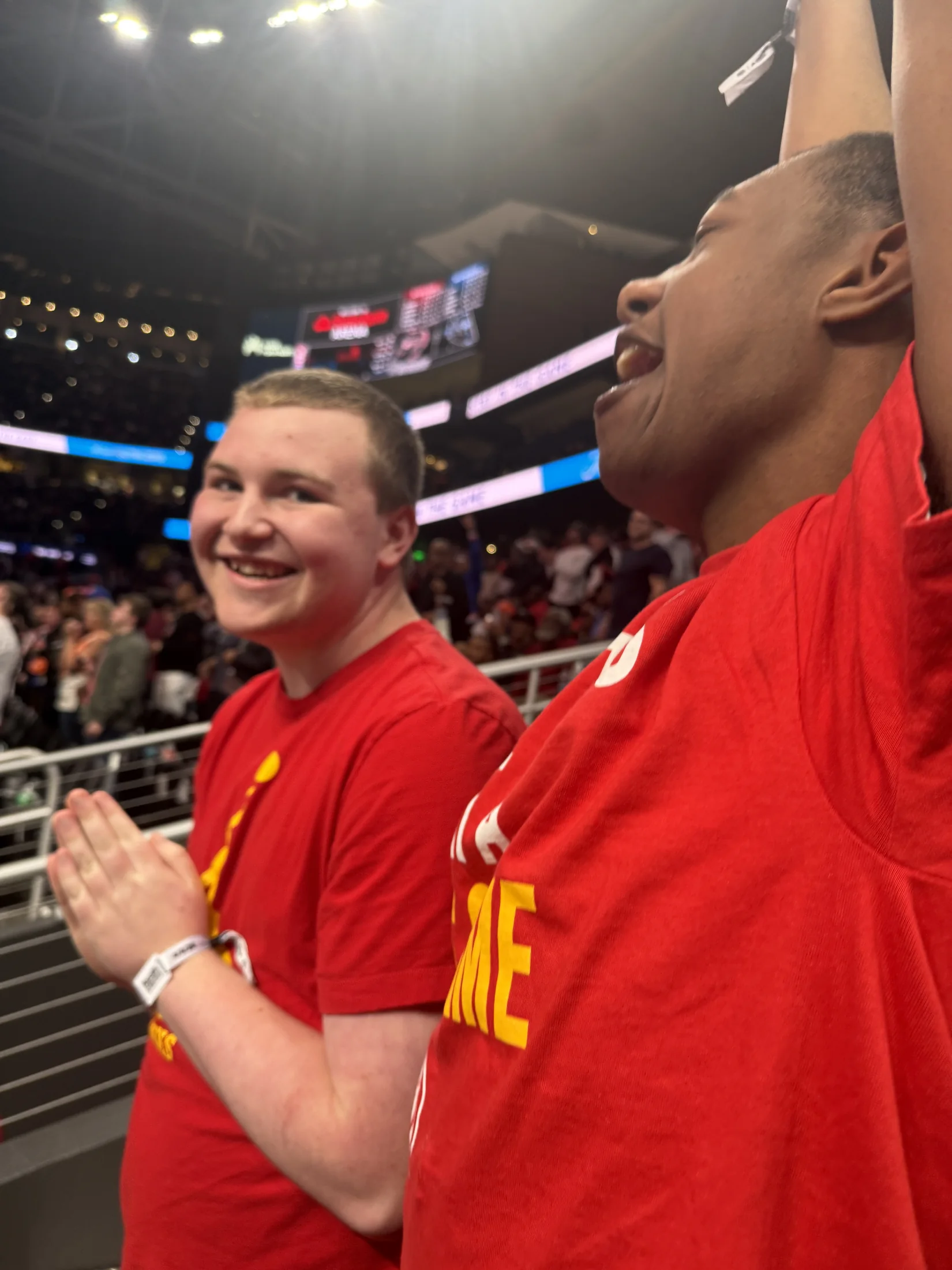 Tommy celebrating and clapping with a friend at a Hawks game